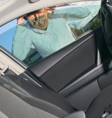 A distressed driver locked out of their car on the side of the road, with the MB Locksmith van approaching in the distance.