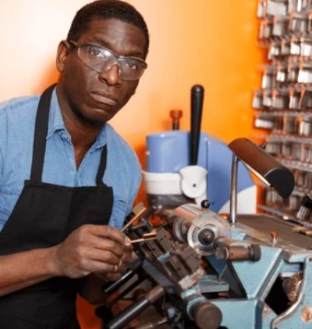 Locksmith cutting keys in a workshop for cars, trucks, and SUVs.