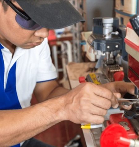 A locksmith in Cary using a key-cutting machine to duplicate a key.