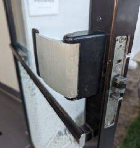 A frustrated office worker standing outside a locked commercial building with the MB Locksmith van arriving in the background.