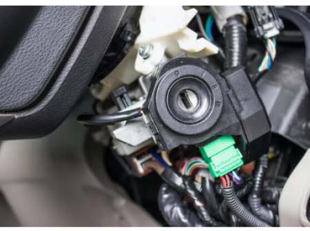 Close-up of a vehicle's ignition switch assembly without the key inserted, revealing electrical connections, serviced by a mobile locksmith.