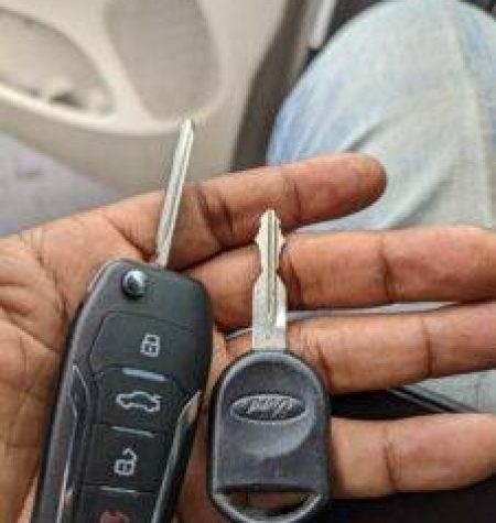 A person holding a pair of broken car keys, with one key snapped apart from its key fob, searches for a "mobile locksmith" nearby.